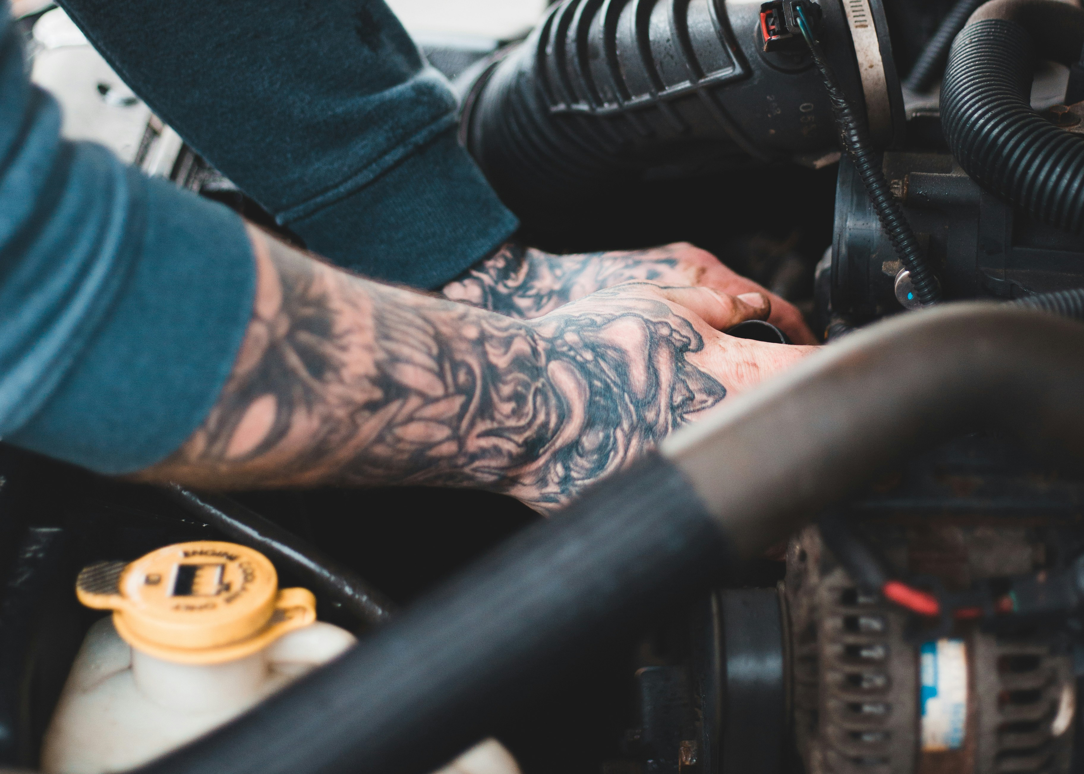 A closeup of a man's hands working inside the engine of a JDM car.