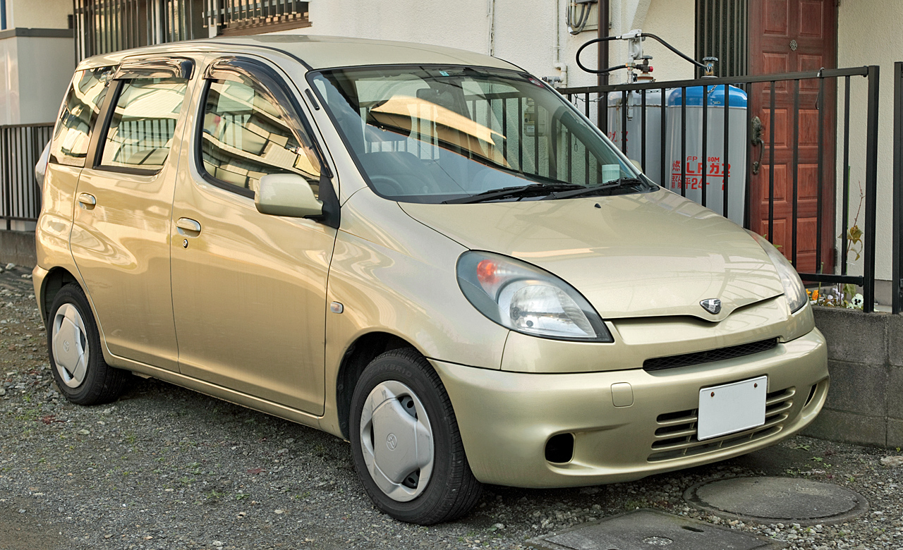 a gold jdm car parked in a driveway.