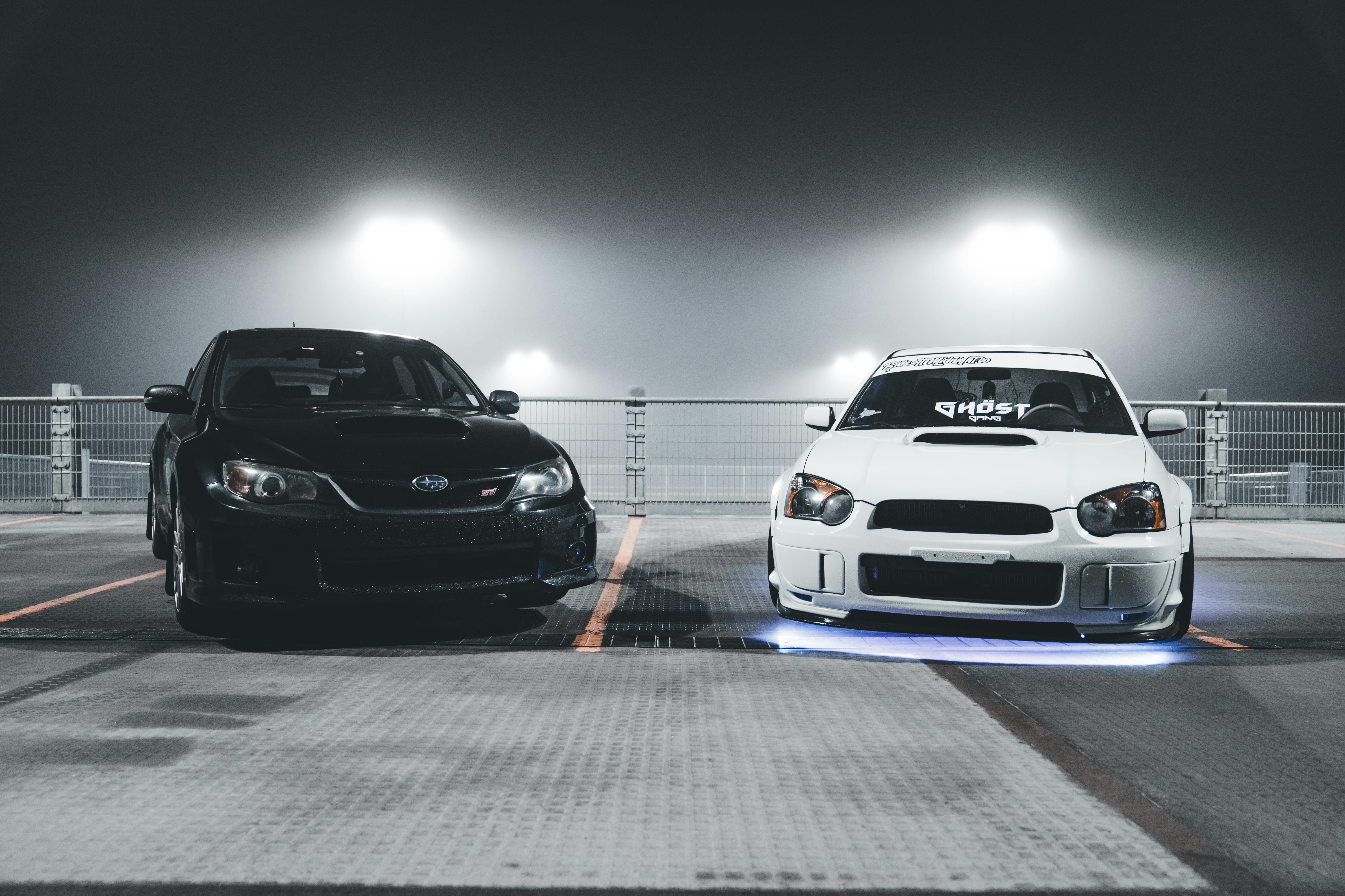 two modified jdm cars in a dark parking lot.
