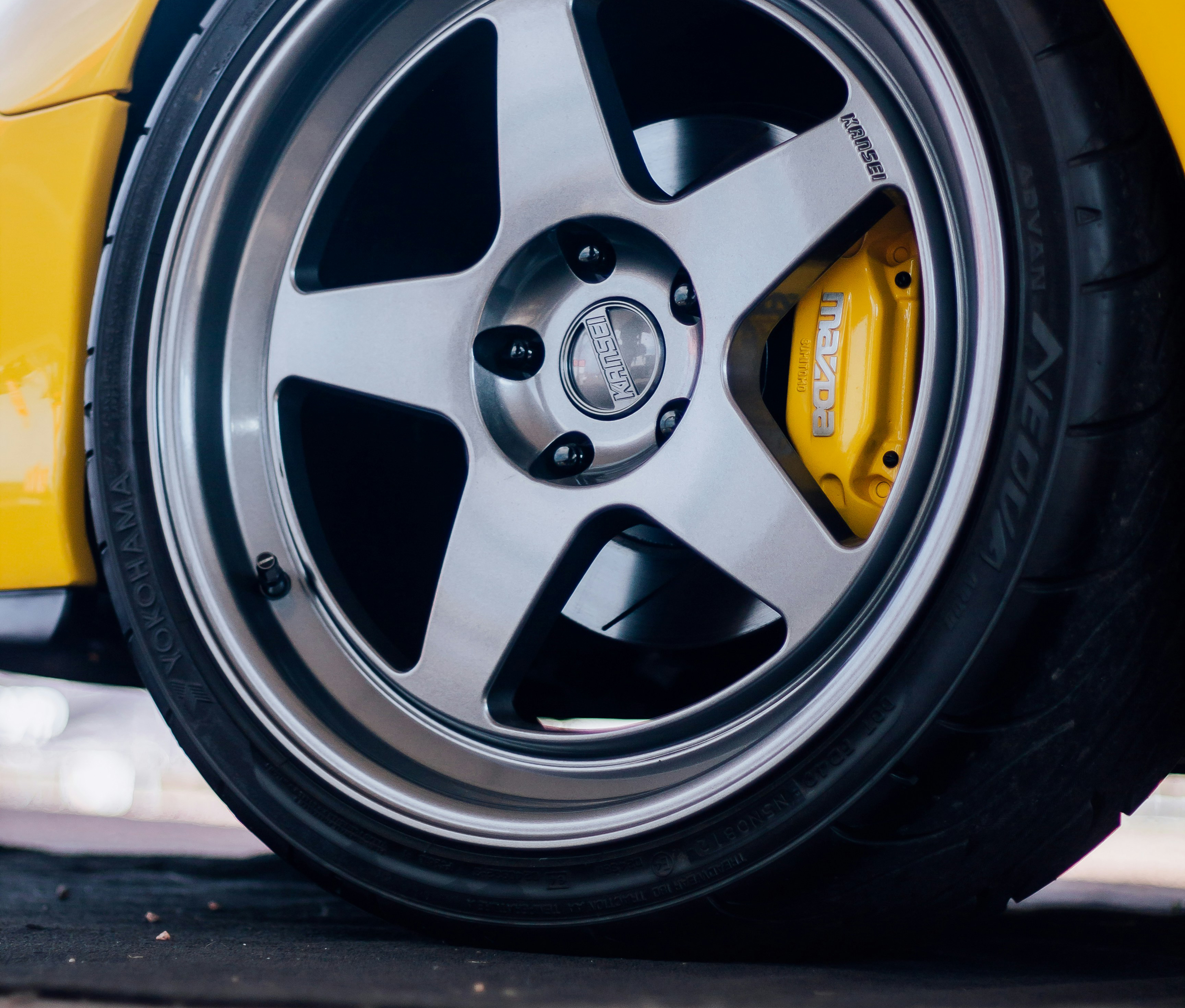 A closeup of a tire of a yellow Mazda RX-7 JDM car