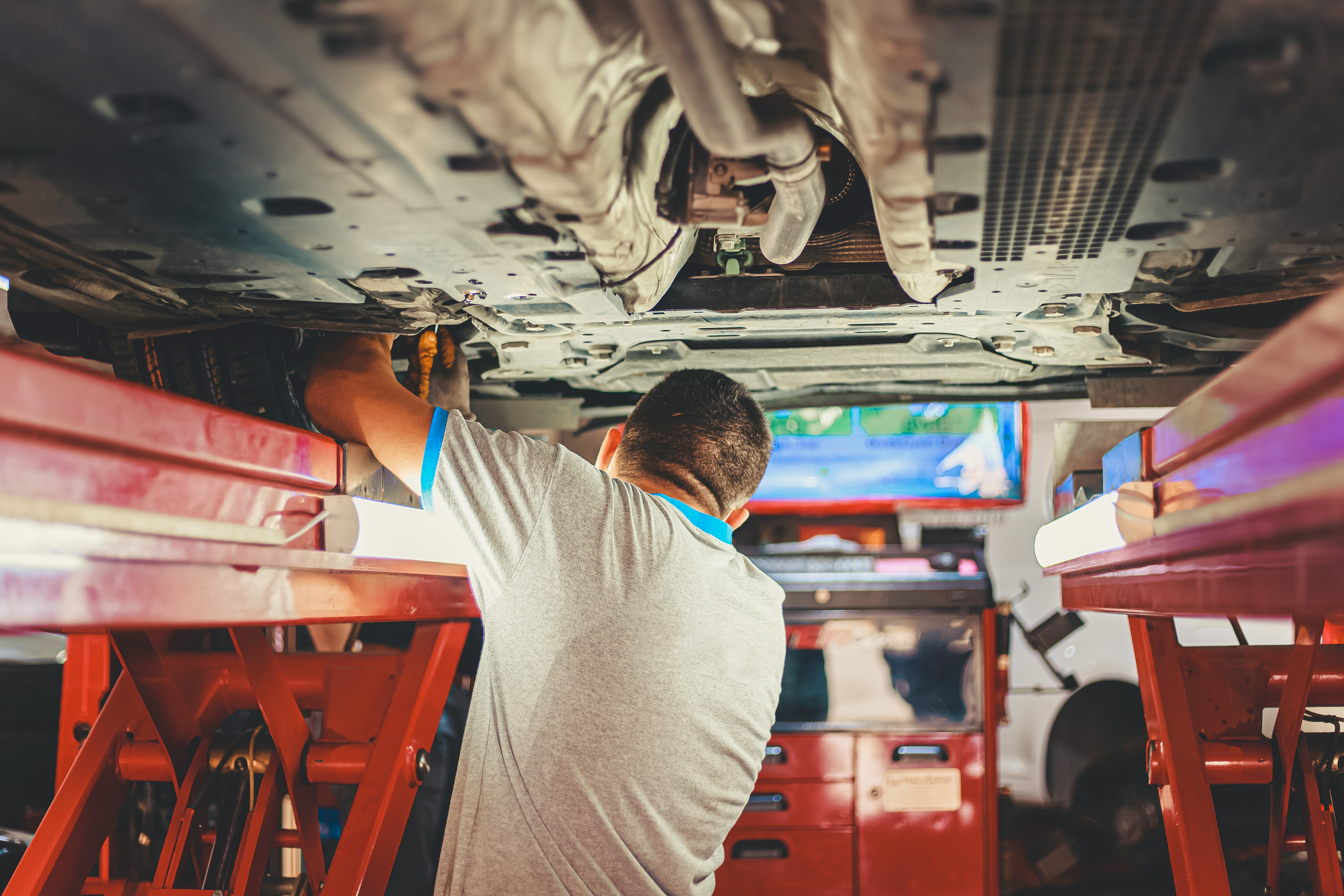 A mechanic working on the bottom of a car, as a part of the Shaken safety inspection.