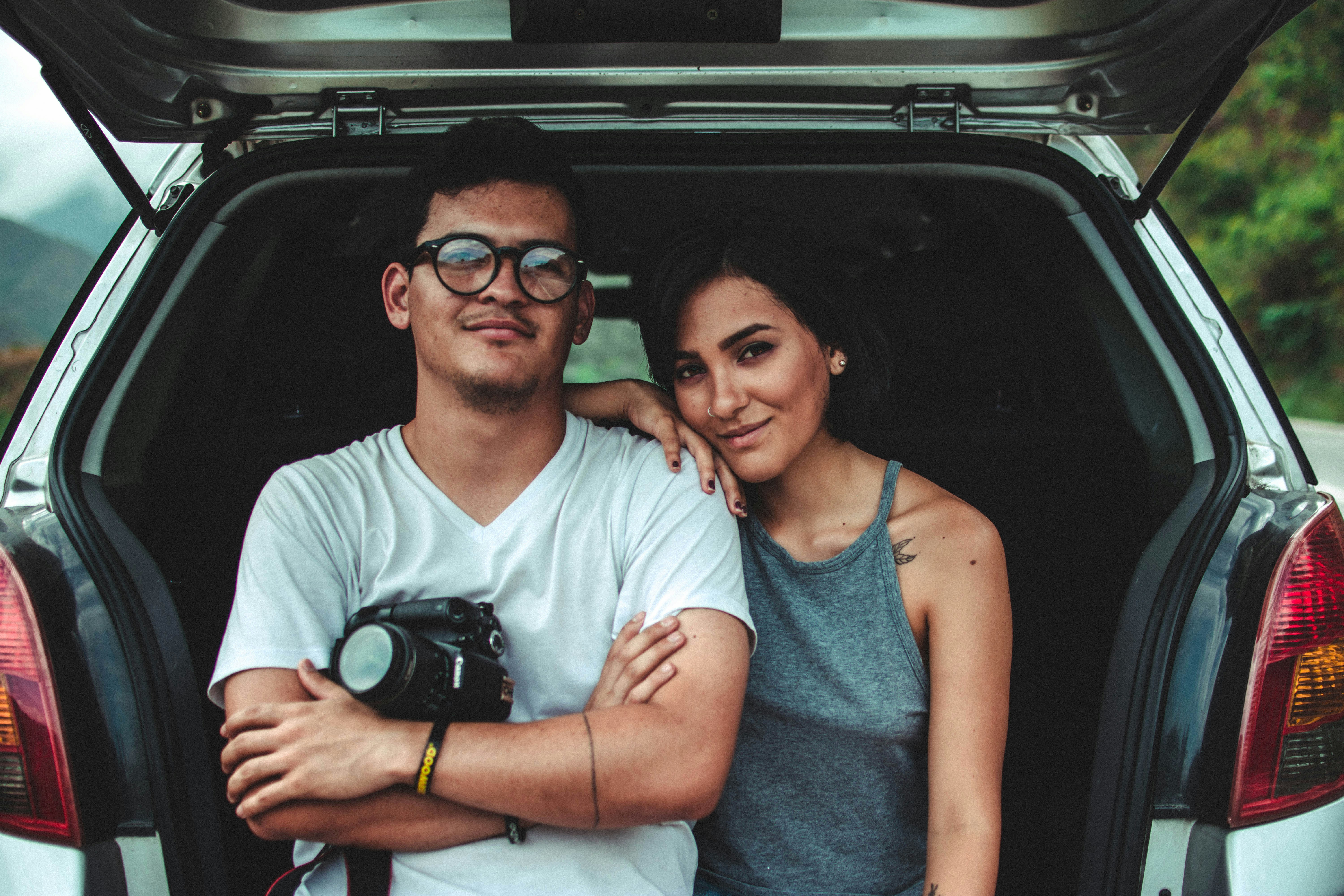 A man and woman happily leaning against the open back hatch of a jdm car.