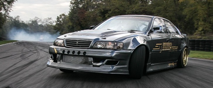 A grey Toyota Chaser JZX100 speeding down a road. This is a JDM car that can be imported in the USA and Quebec in 2024.