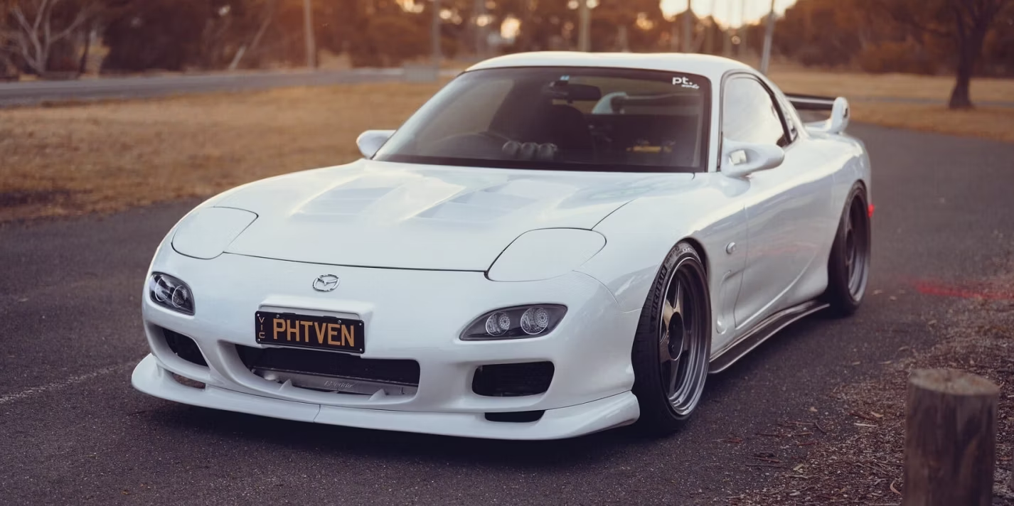 A white Mazda RX-7 parked in an empty parking lot. This is a JDM car that can be imported in the USA and Quebec in 2024.