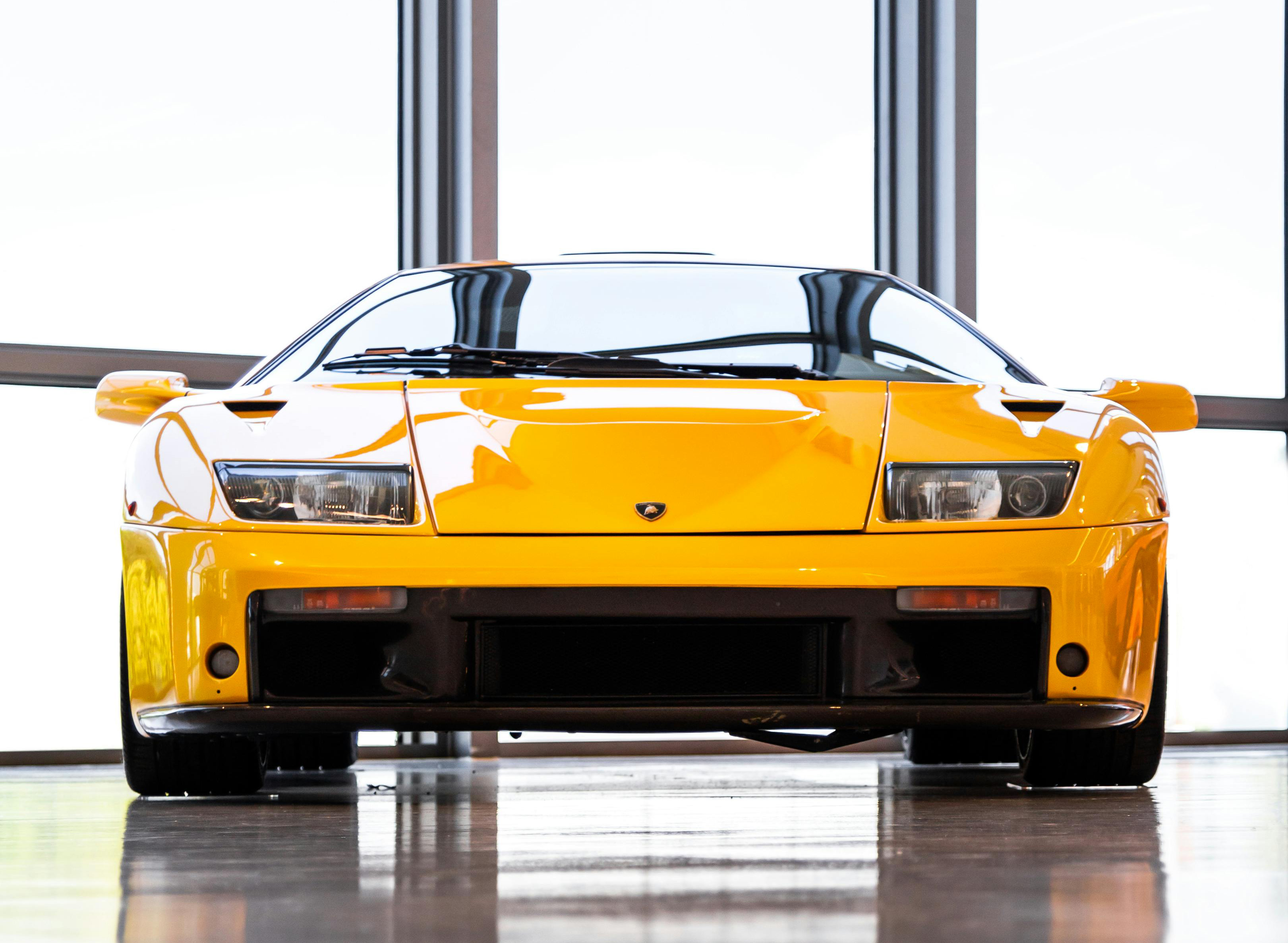 A yellow Lamborghini Diablo VT jdm car in a showroom.